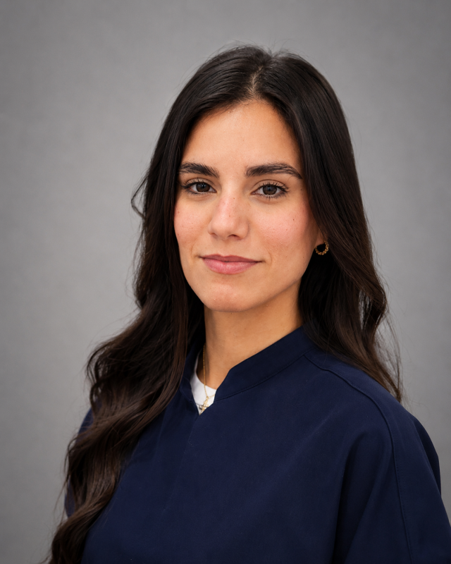 Portrait of Lissette, dental team member in navy scrubs smiling at the camera