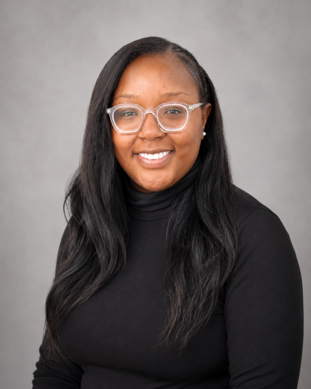 Portrait of Miranda, dental office team member wearing glasses and black turtleneck