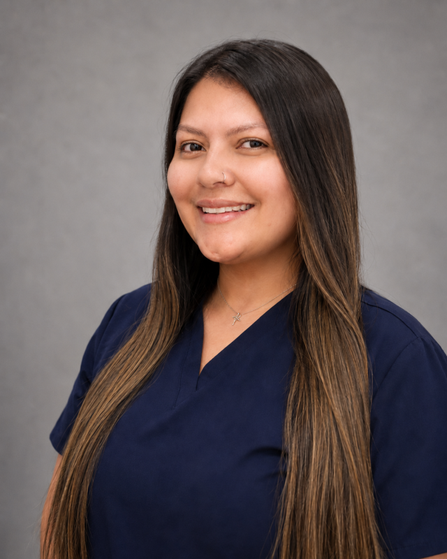 Portrait of Vanessa, dental team member in blue scrubs smiling at the camera